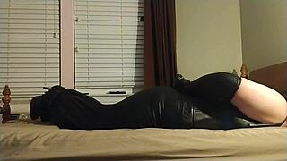 crossdresser ties himself up in tight bondage gear