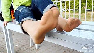 Tan nylon soles peek from blue jeans, teasing toes on the bench outdoors